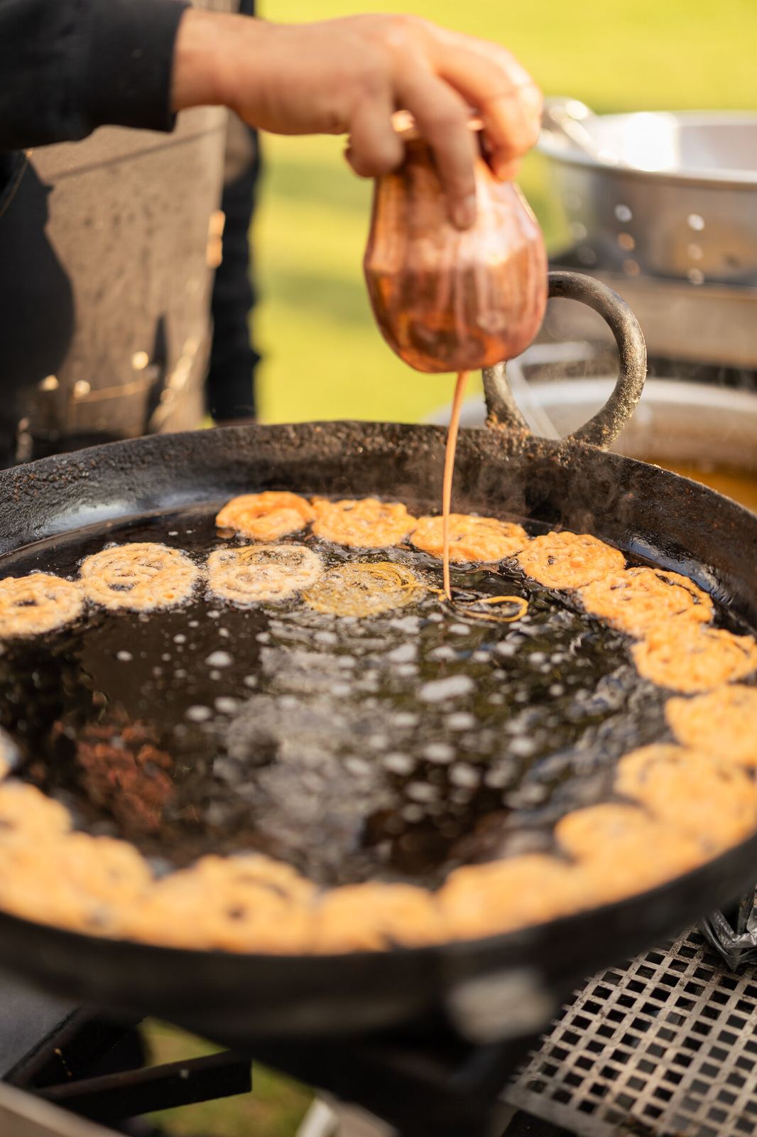 Chef preparing fresh jalebi at a live cooking station during a wedding reception